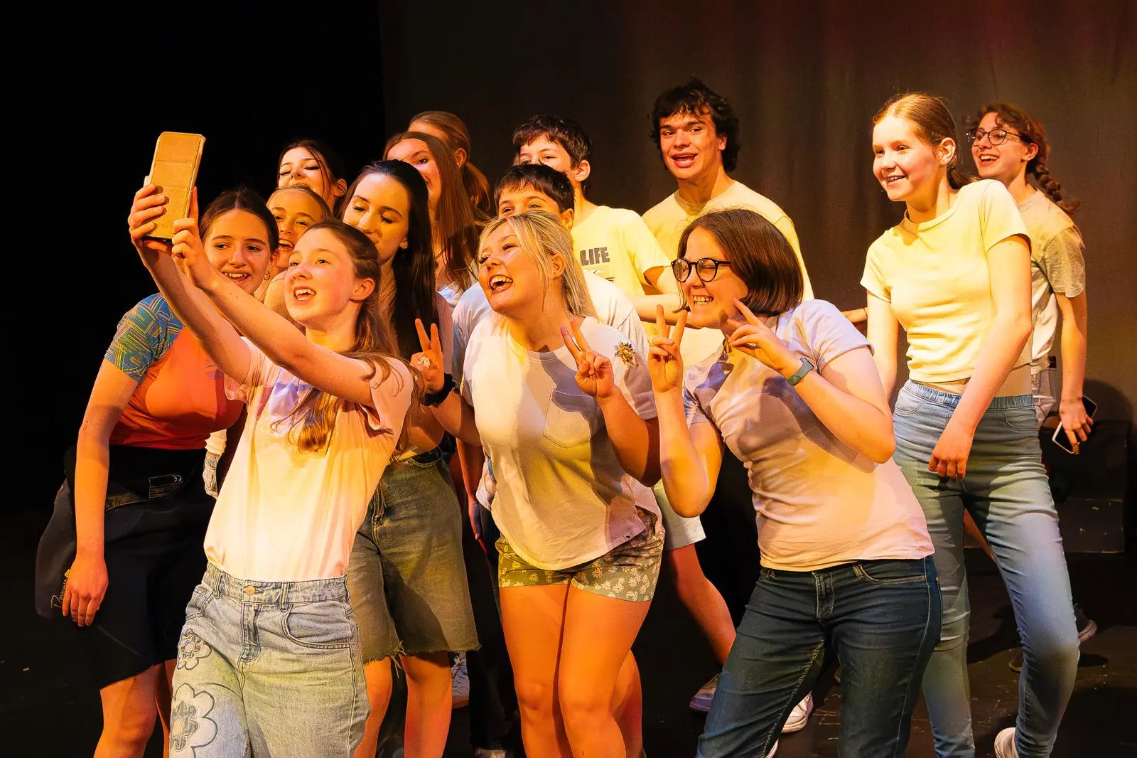 WhatsApp Image 2025-04-29 at 11.25.22 (6) group scene of young actors taking a selfie in performance of Mia and The Fish