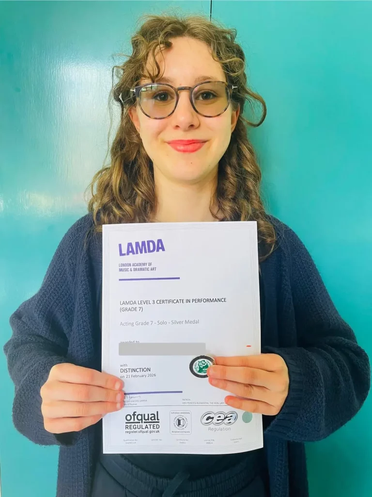 Female student holding their Lamda Level 3 Certificate in Performance Level 7, achieving a distinction
